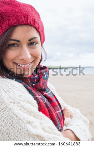 Close up portrait of a young woman in knitted hat and pullover smiling at the beach
