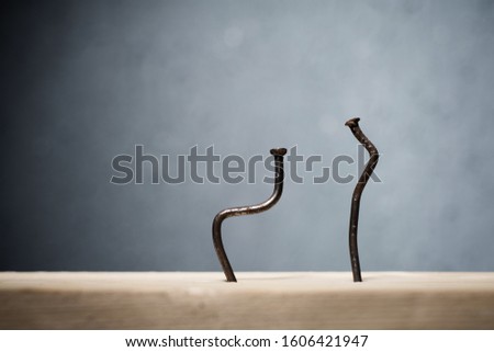 Two bent nails driven into a board. Concept stoop, sciatica and degenerative disc disease - image Royalty-Free Stock Photo #1606421947