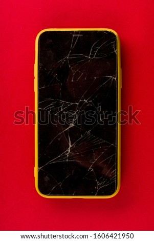 Smartphone with broken screen on red background - image