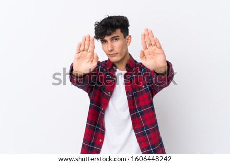 Young Argentinian man over isolated white background making stop gesture and disappointed