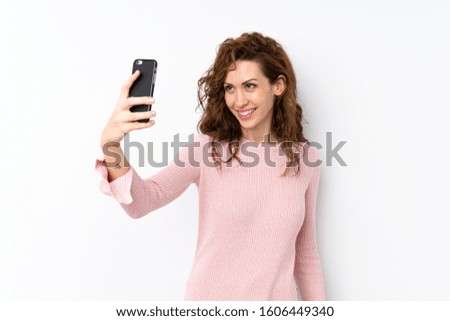 Young pretty woman over isolated background taking a selfie with the mobile