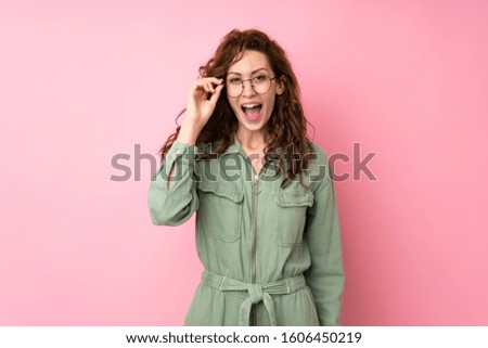 Young pretty woman over isolated pink background with glasses and surprised