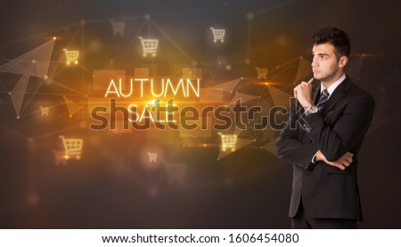 Businessman with shopping cart icons and AUTUMN SALE inscription, online shopping concept