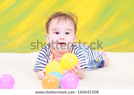 little funny boy in sport costume with  color ball in yellow background.