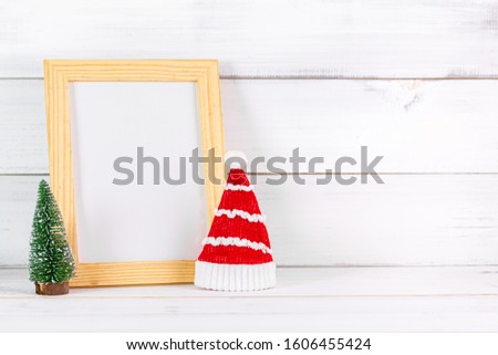 Christmas hat with pine tree and empty photo frame on white wood background with copy space