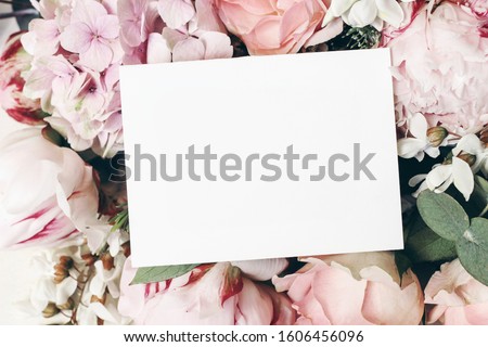 Wedding, birthday stationery mock-up scene. Blank paper greeting card, invitation. Decorative floral composition. Closeup of  pink roses petals, peonies, hydrangea flowers and eucalyptus leaves.