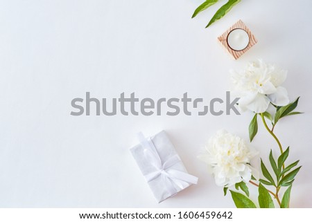 Flat lay composition with white peonies and gift box on a white background