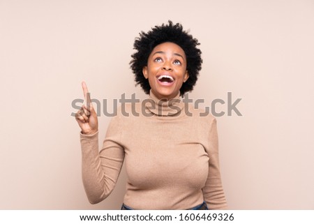 African american woman over isolated background pointing up and surprised