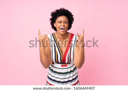 African american woman over isolated pink background making rock gesture
