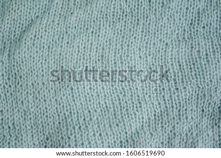 part of the fabric knitted on knitting needles. close-up of a knit fabric loop. blue gray background