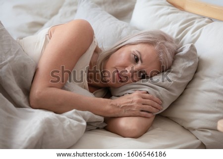 Unhappy elderly woman lying in bed at home thinking pondering over life problems, mourning or yearning, upset sad senior female relax in bedroom feel unwell or stressed suffering from insomnia Royalty-Free Stock Photo #1606546186