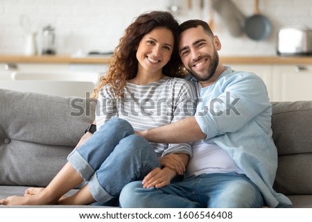 Portrait of young 35s just married couple in love posing photo shooting seated on couch in modern studio apartments, concept of capture happy moment, harmonic relationships, care and sincere feelings Royalty-Free Stock Photo #1606546408