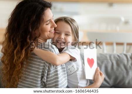 Loving pre-school daughter preparing for mother surprise gave her handmade card with red heart symbol of love, 8 eight march spring holiday International Women or Mothers Day celebration event concept