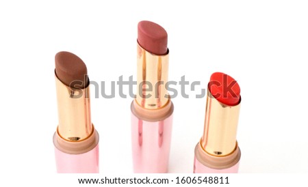 Brown and red lipsticks with pink cap on white background.