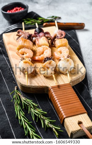 Grilled shish kebab with seafood, shrimp, octopus, squid and mussels. Gray background. Top view