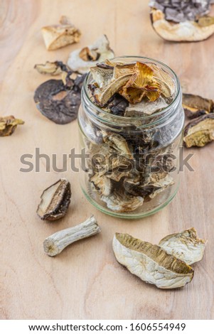 Dried porcini mushrooms in a storage jar on wooden background. Vertical orientation-Image