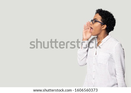 African girl pose aside on grey background looking at copy space holds hand near mouth call somebody speaks loud make announcement about grand sell-out, falling prices better commercial offer concept Royalty-Free Stock Photo #1606560373