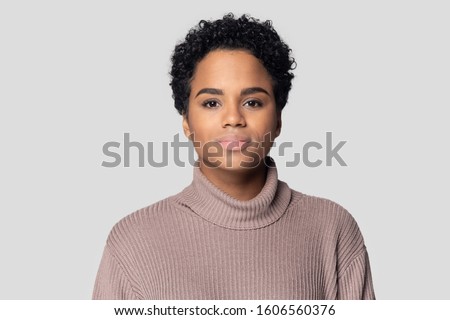 Head shot portrait African young woman having short black hairs wears knitted sweater posing isolated on gray background, serious beautiful 20s mixed-race girl look at camera, natural beauty concept Royalty-Free Stock Photo #1606560376