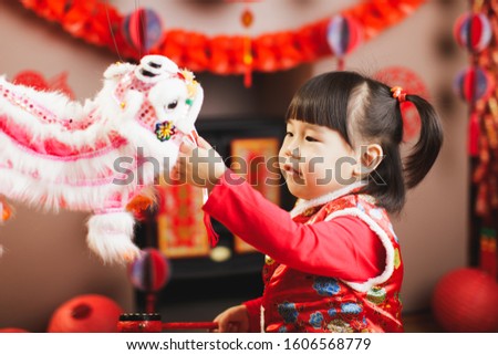 Chinese baby girl with traditional dressing up and holding dancing lion with " Zhao cai jin bao" meaning "more wealth coming"  celebrate Chinese new year