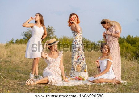 The company of stylish happy female friends having fun on outdoor retro style picnic party.