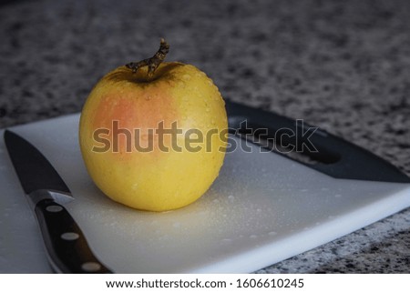 An Opal apple on a cutting board in natural light