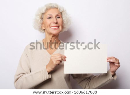 Portrait of happy senior woman with blank advertising board or copy space