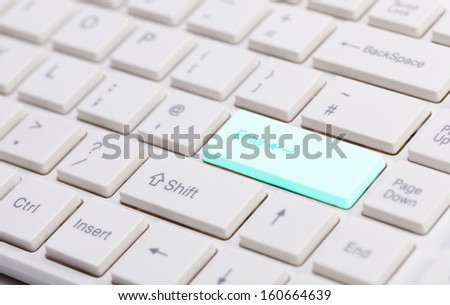 Close up of white keyboard with shallow depth of field and glowing blue enter button for concepts of technology the internet and communications