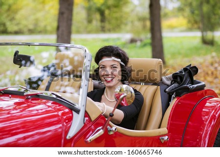 Smiling widely young woman after red car wheel