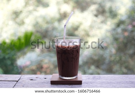 Glass of cocoa cool drink served on table forest view background