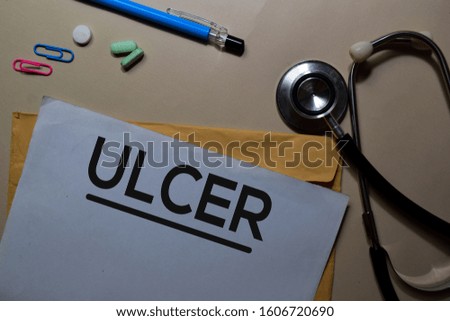 Ulcer text on document above brown envelope and stethoscope. Healthcare or medical concept