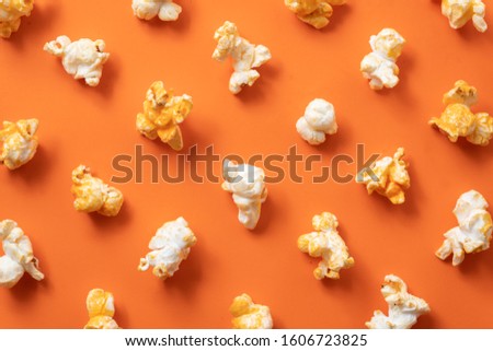 Cheese popcorn sorted like a polka dot on orange background.