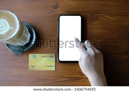 Close up of woman using phone,sending massages phone blank credit card texture on wood table within coffee shop.