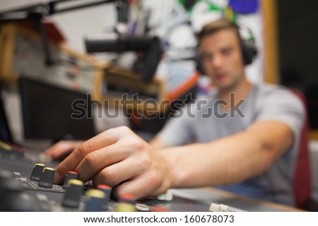 Handsome radio host moderating touching switch in studio at college