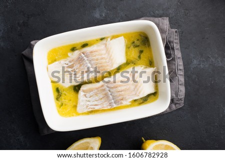 Steamed cod fillet butter-lemon sauce with herbs in the oven. Top view. In a baking dish. Healthy eating