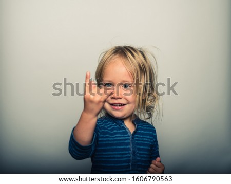 Studio portrait of toddler doing heavy metal sign with his fingers