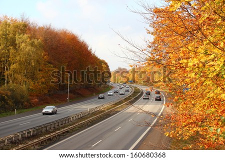 Busy highway through autumn forest with beautiful colors