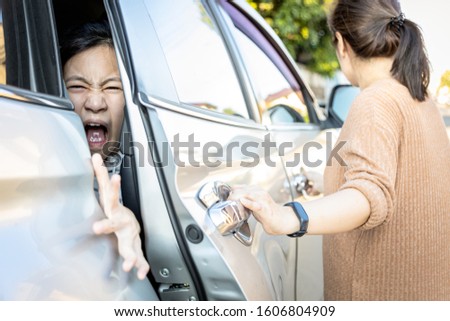 Accident,hand slammed the door,mischievous child girl was pinched her hand or fingers in the car door,asian daughter shouted in pain,woman or mother closed the car door without careful,inadvertently  Royalty-Free Stock Photo #1606804909