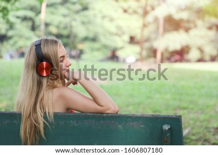 A beautiful Caucasian woman relaxing in a park with listen to music for portrait cute girl resting and lifestyle concept