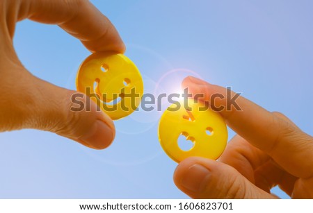 people hand holding yellow emoticon smiley face icon symbol on blue sky background with copy space, for a positive mindset in business marketing and beautiful world peace concept