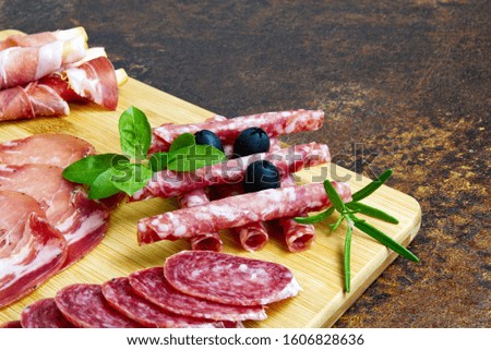 Meat and cheese plate antipasti snack with Prosciutto ham, Parmesan, Blue cheese, Cantaloupe melon and Olives on olive wood serving board on dark stone background