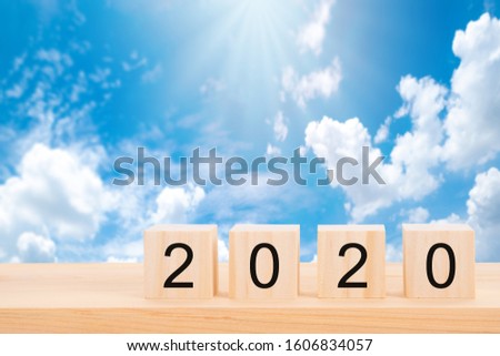 Happy new year 2020 text on wooden cubes on wooden pine table and blur blue sky background. Banner with copy space for text. 


