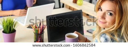 Close-up of business people working with computers at desk in creative modern office. Freelance workers sitting with cups of tea. Designer agency concept