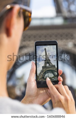 Woman in Paris taking pictures in front of Eiffel Tower with her Smart Phone