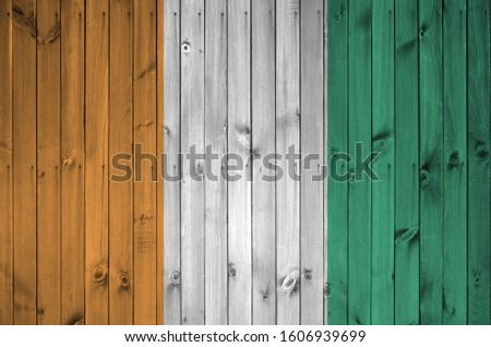 Ivory Coast flag depicted in bright paint colors on old wooden wall. Textured banner on rough background