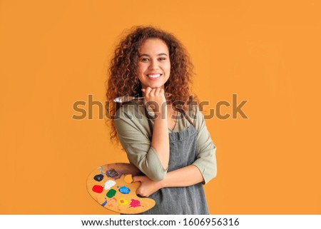 Beautiful female African-American artist on color background