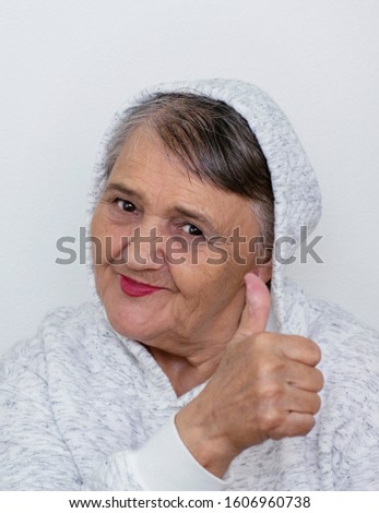 Funny grandma's portraits. An elderly lady makes a hipster gesture with her hand "OK". Fashion hipster woman having fun. Funny moments with a woman's grandmother. Lifestyle and concepts of people