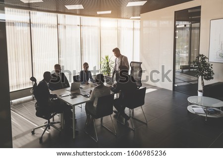 Silhouettes of people sitting at the table. A team of young businessmen working and communicating together in an office. Corporate businessteam and manager in a meeting Royalty-Free Stock Photo #1606985236