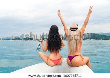 beautiful happy booty girls in bikinis having fun on yacht. two fingers in letter V