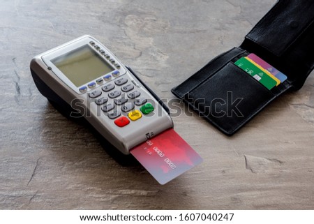 Bank terminal for payments and plastic card on grey stone background
