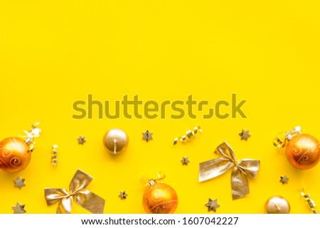 New Year decoration background - golden balls and bows on yellow desk top-down frame copy space